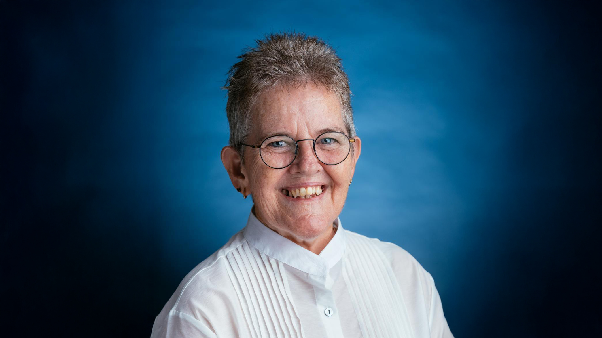 QCT board chair Wendy Patton wearing a blue button up shirt in front of the QCT blue background