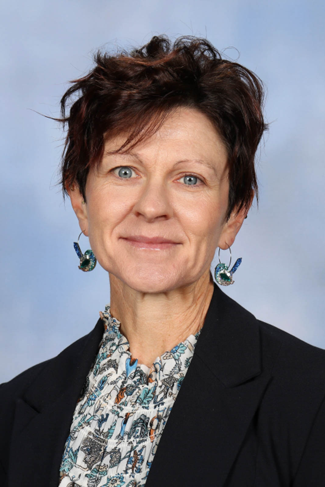 Headshot of Amanda wearing bird earrings, a black blazer and floral top.