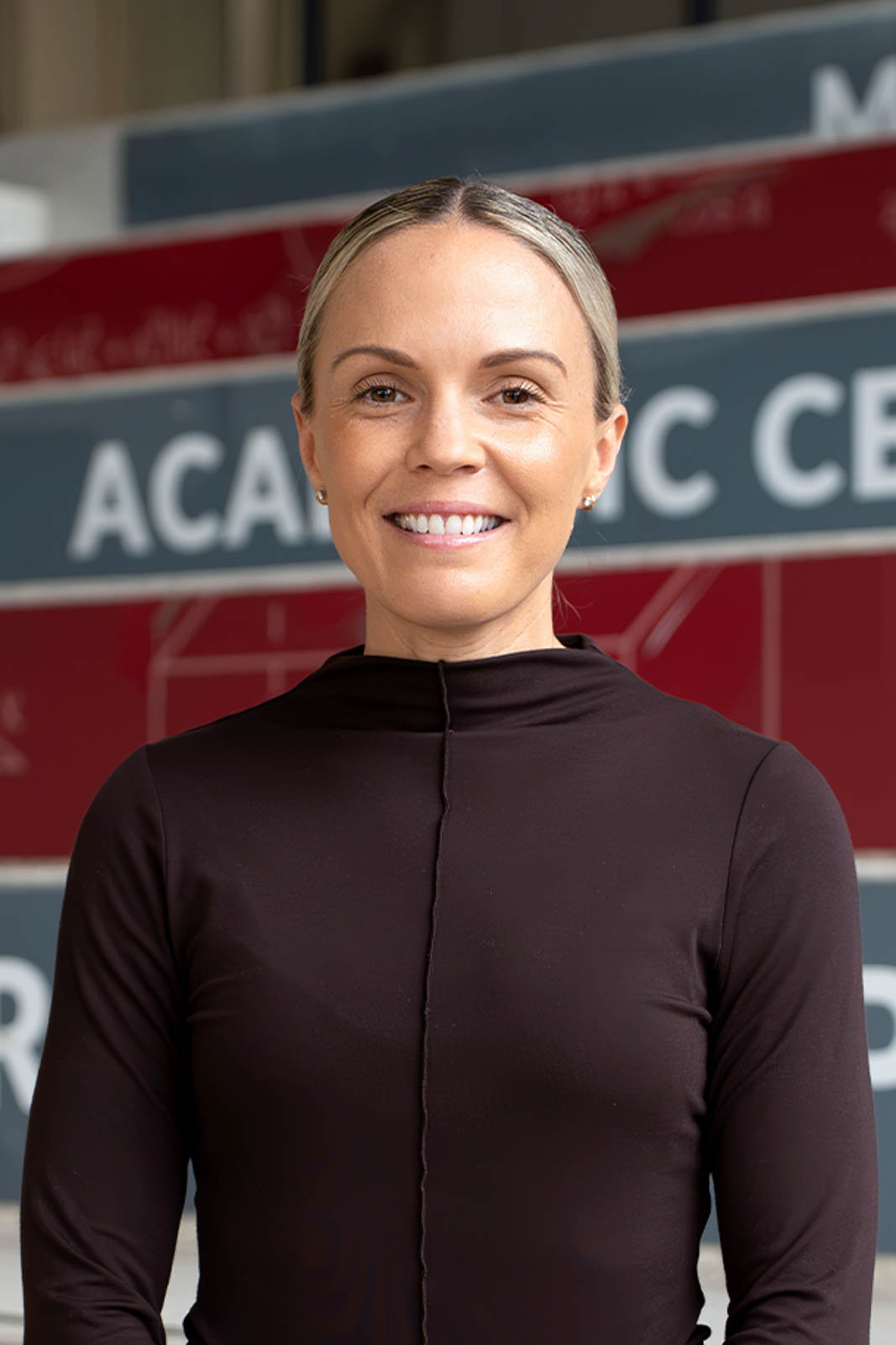 Headshot of Sara in front of an academic centre building.