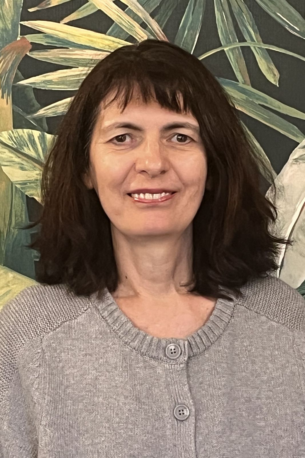 Headshot of Irena in front of a painted tree background.