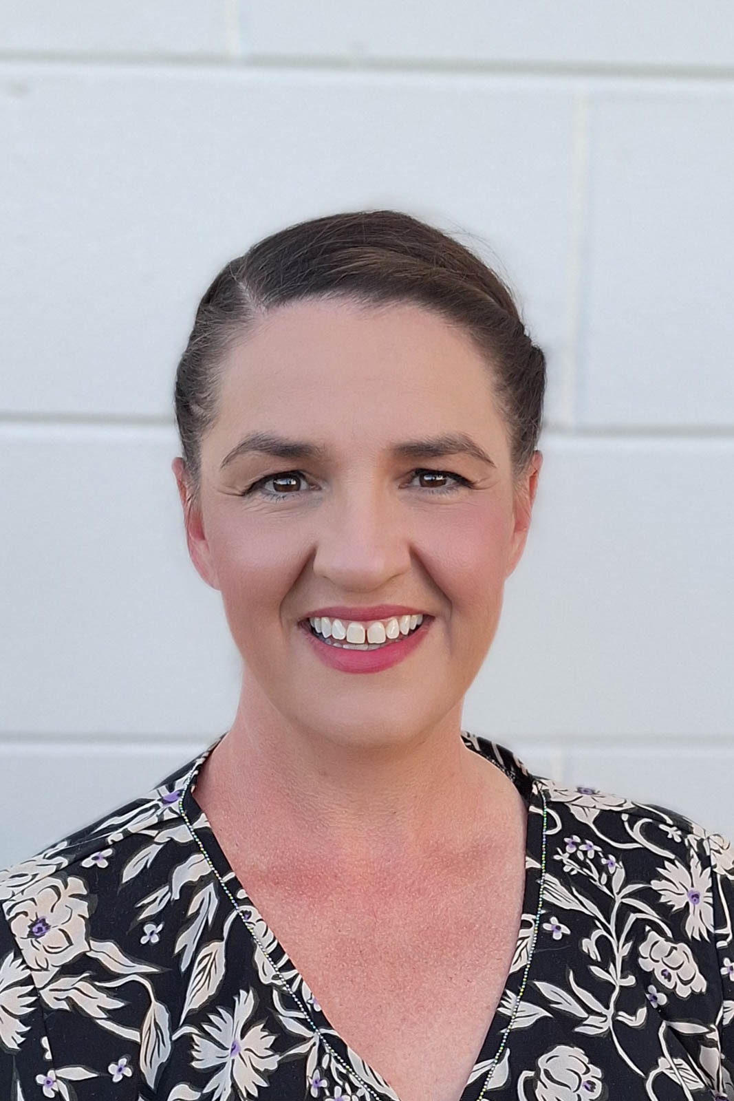 Outdoor headshot of Laura-Beth in a floral-patterned blouse.