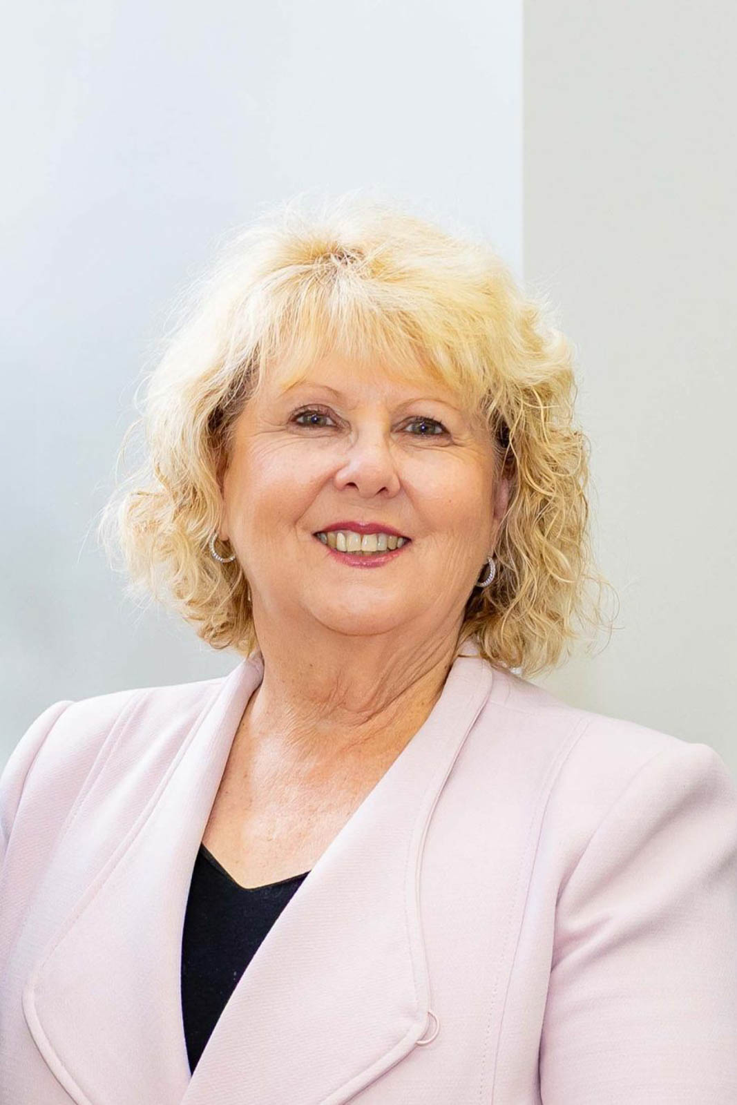 Headshot of Lee in a light pink blazer.
