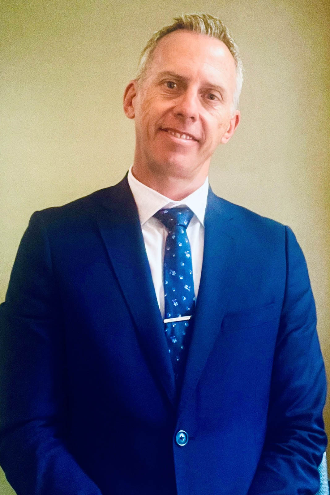Headshot of Michael Hall in a blue suit.