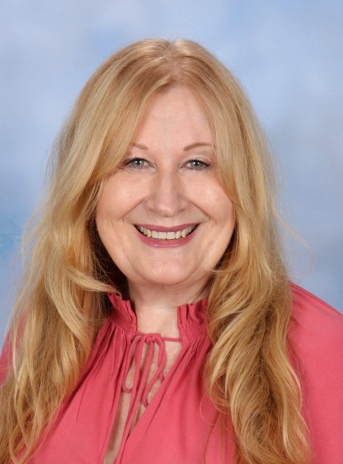 Headshot of Sharon in a coral pink top.